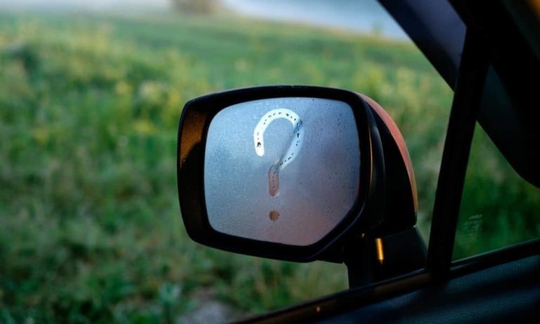 A car windscreen mirror with a question mark drawn in condensation